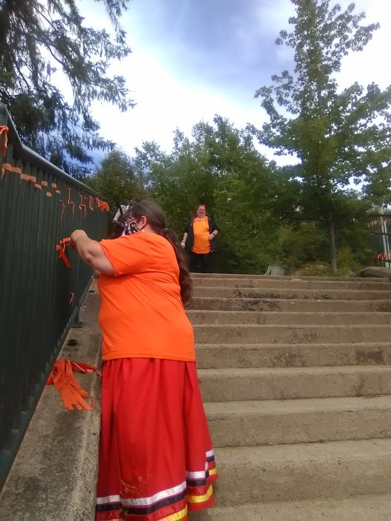 Theresa Buker, founder of the Muskoka Indigenous Friendship Community, tying ribbons at Bracebridge Falls
