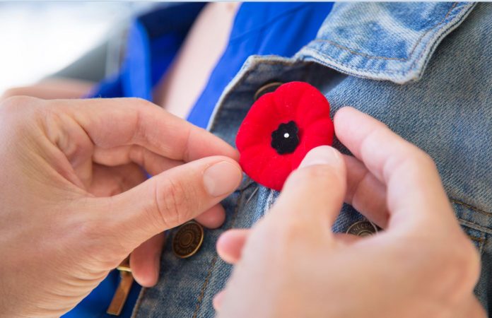 A Remembrance Day poppy pin is placed on a person's jacket