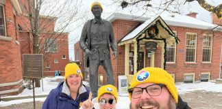 Gravenhurst volunteers wear their yellow Coldest Night of the Year toques alongside the statue of Dr. Norman Bethune