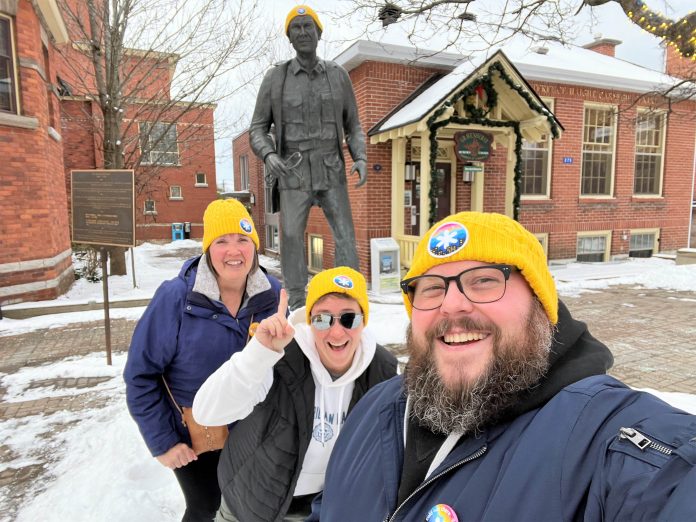 Coldest Night of the Year (CNOY) Gravenhurst volunteers wear their yellow Coldest Night of the Year toques alongside the statue of Dr. Norman Bethune