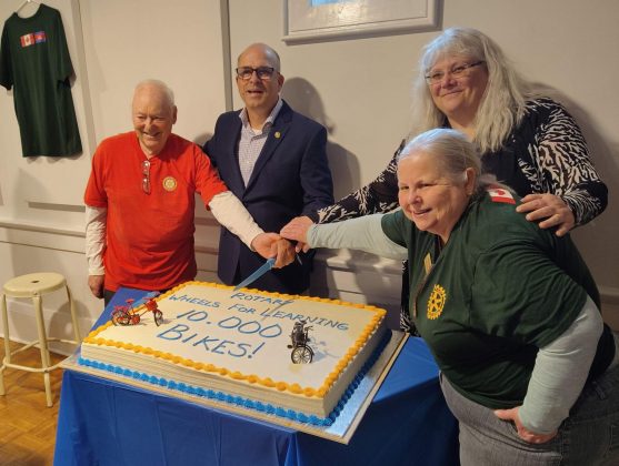 Rotary Wheels for Learning (RWFL) chair and field coordinator Mike Cole cuts the cake with members of the Gravenhurst Rotary Club