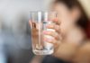 Drinking water: A woman holds out a glass of water against a blurred background