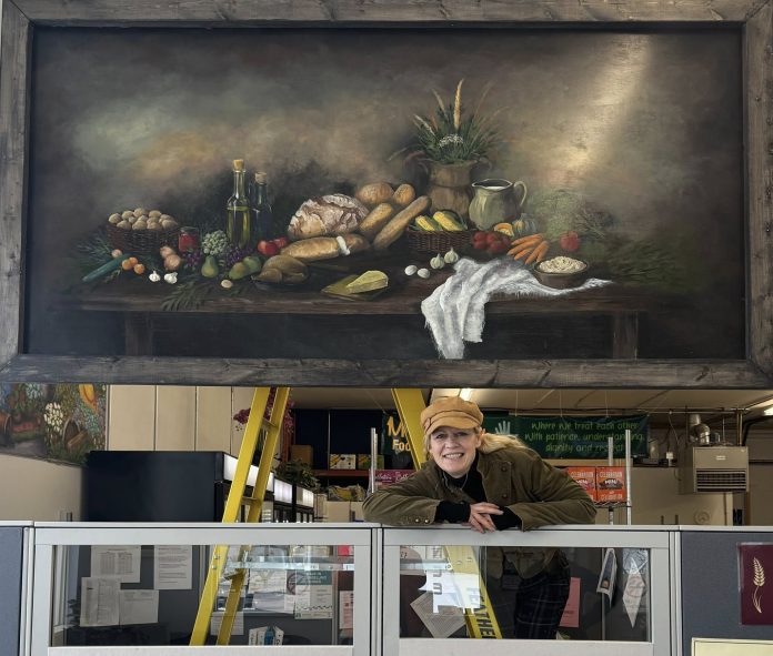 Kimberly Rideout, under her donated mural to the Manna Food Bank, Bracebridge, Ont.